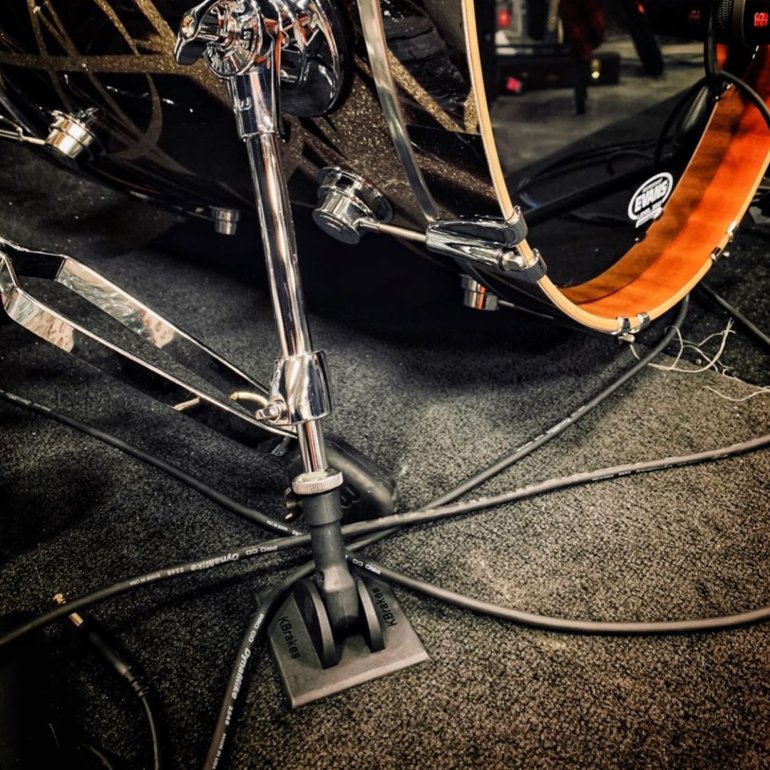 KBrakes shown on a drum kit on stage with cables running on the floor