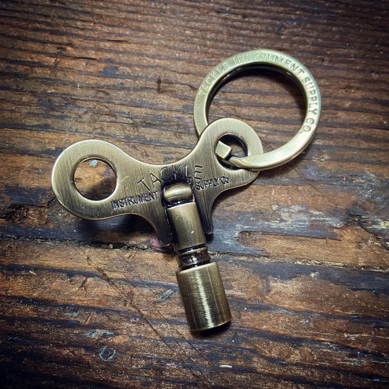 Timekeepers Drum Key from Tackle shown in antique brass unpacked at an old wooden surface